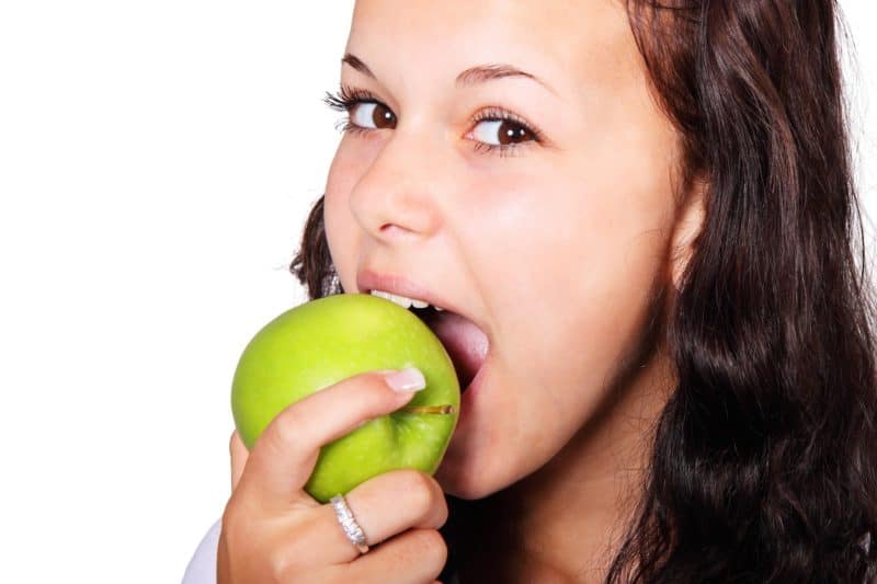 woman eating apple Food That Promote Oral Health 2