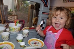 Smiling little girl playing with play dishes