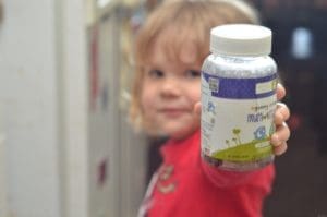Vitamins for kids. little girl holding a bottle Natural Dynamix for Kids!