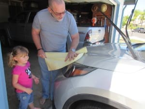 Grandpa and granddaughter cleaning car
