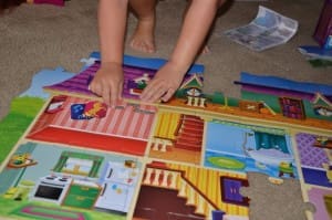 Little girl putting together a dollhouse puzzle for kids
