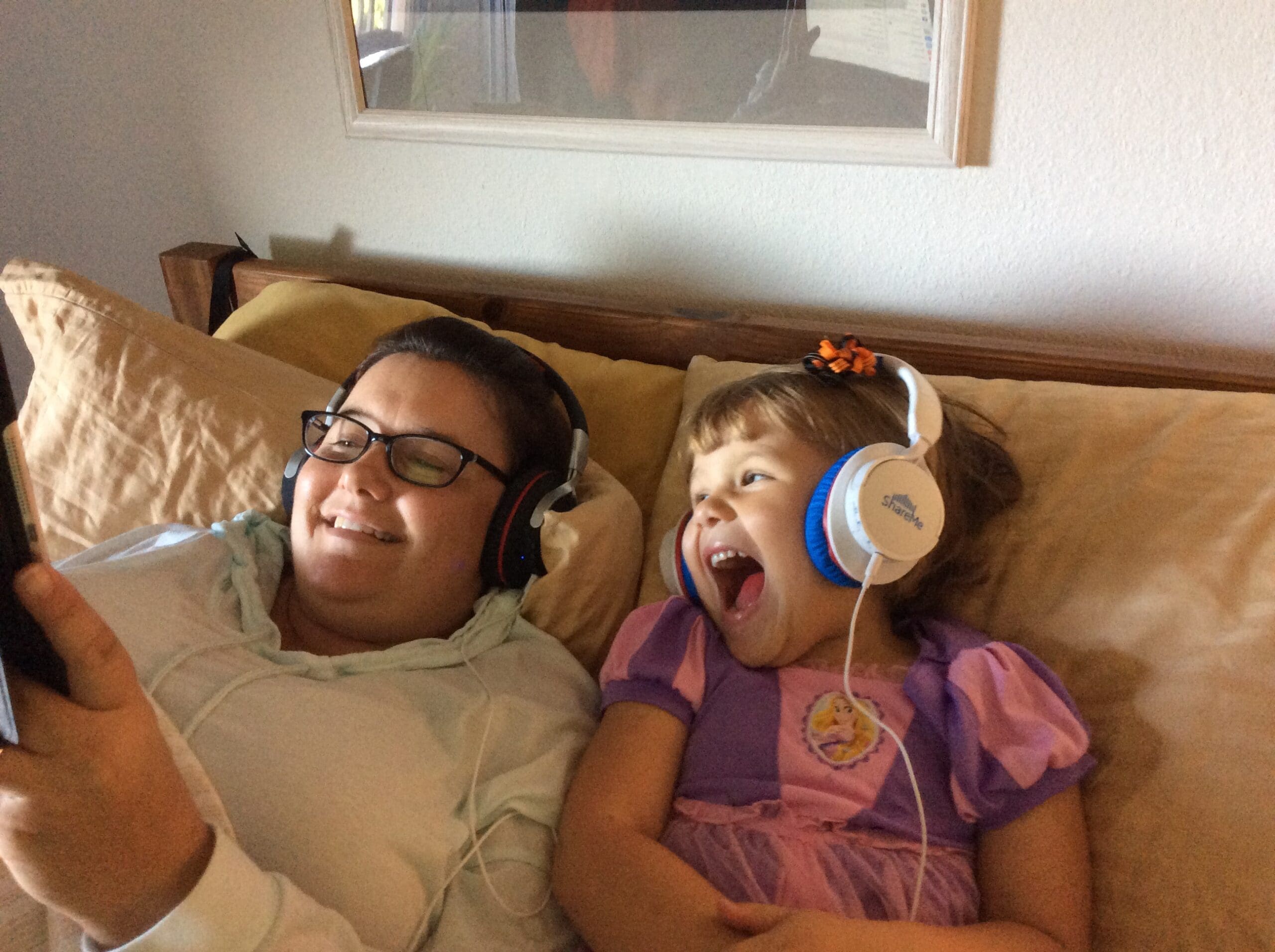 Mom and daughter with headphones watching a movie on iPad