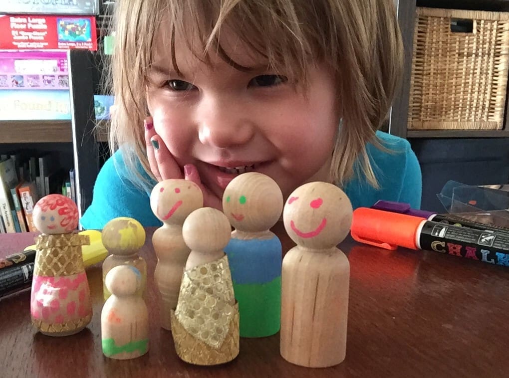 Little girl smiling with wooden dolls