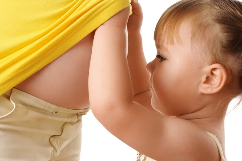 Little girl looking at pregnant moms belly