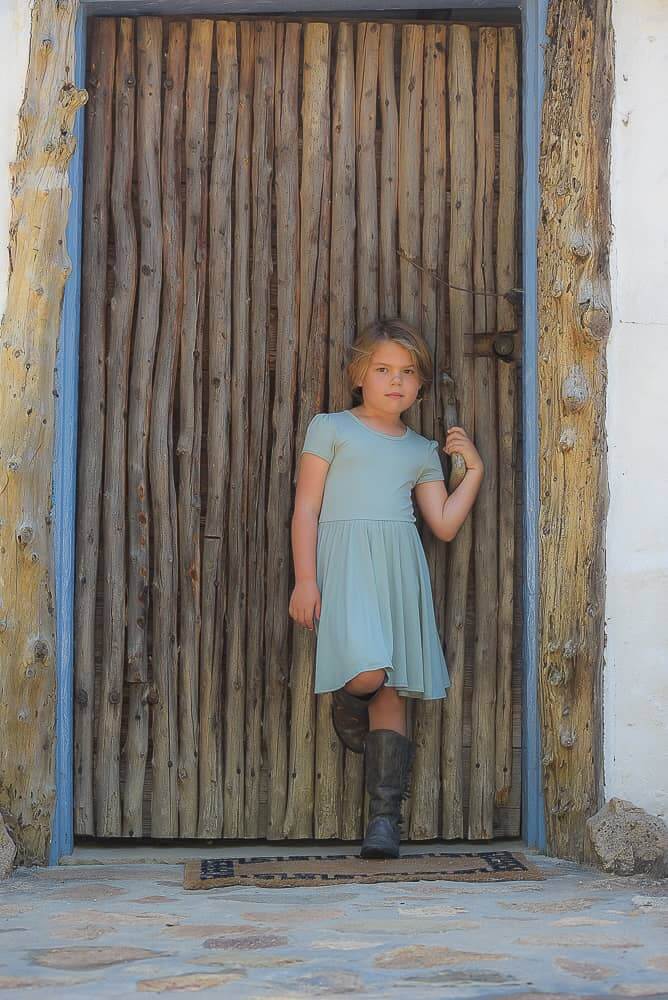 Little girl in from of wood door
