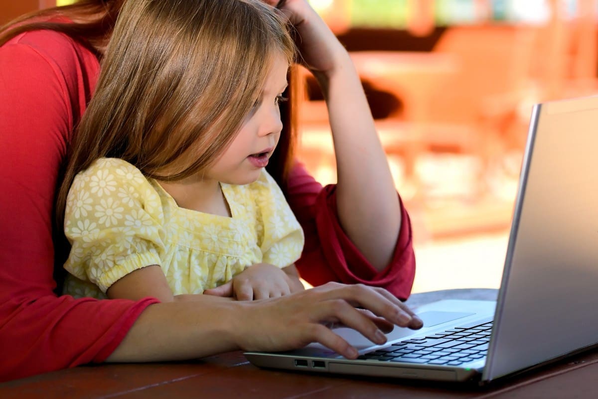 Little Girl at laptop with Mom Working From Home