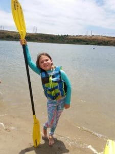 Little girl in life vest with paddle