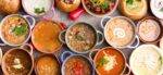 Several colorful bowls of different kinds of soup. Some are smooth, some are rustic, and some have garnishes like cheese and herbs. Food-Related Holidays