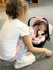 little girl with a baby doll in a carrier