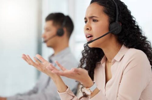 A woman with an exasperated expression gesturing with two open palms to her monitor. She is wearing a headset. Tax Professionals