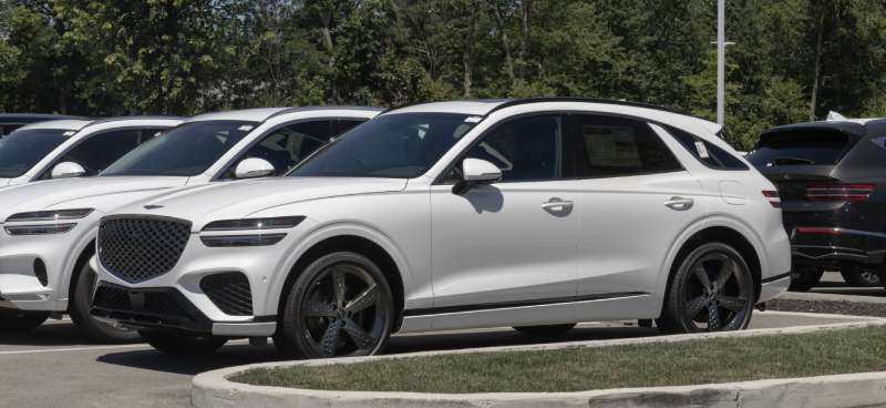 A new Genesis GV70 Sport stock Turbochargers  SUV is parked in a dealership lot surrounded by similar vehicles.