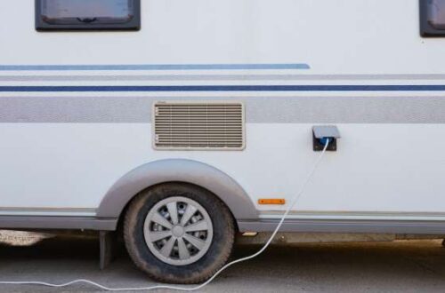 An older RV parked near an electrical box. There's a wire running from the RV to the electrical system.