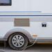 An older RV parked near an electrical box. There's a wire running from the RV to the electrical system.