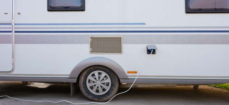 An older RV parked near an electrical box. There's a wire running from the RV to the electrical system. Electrical Failure in an RV