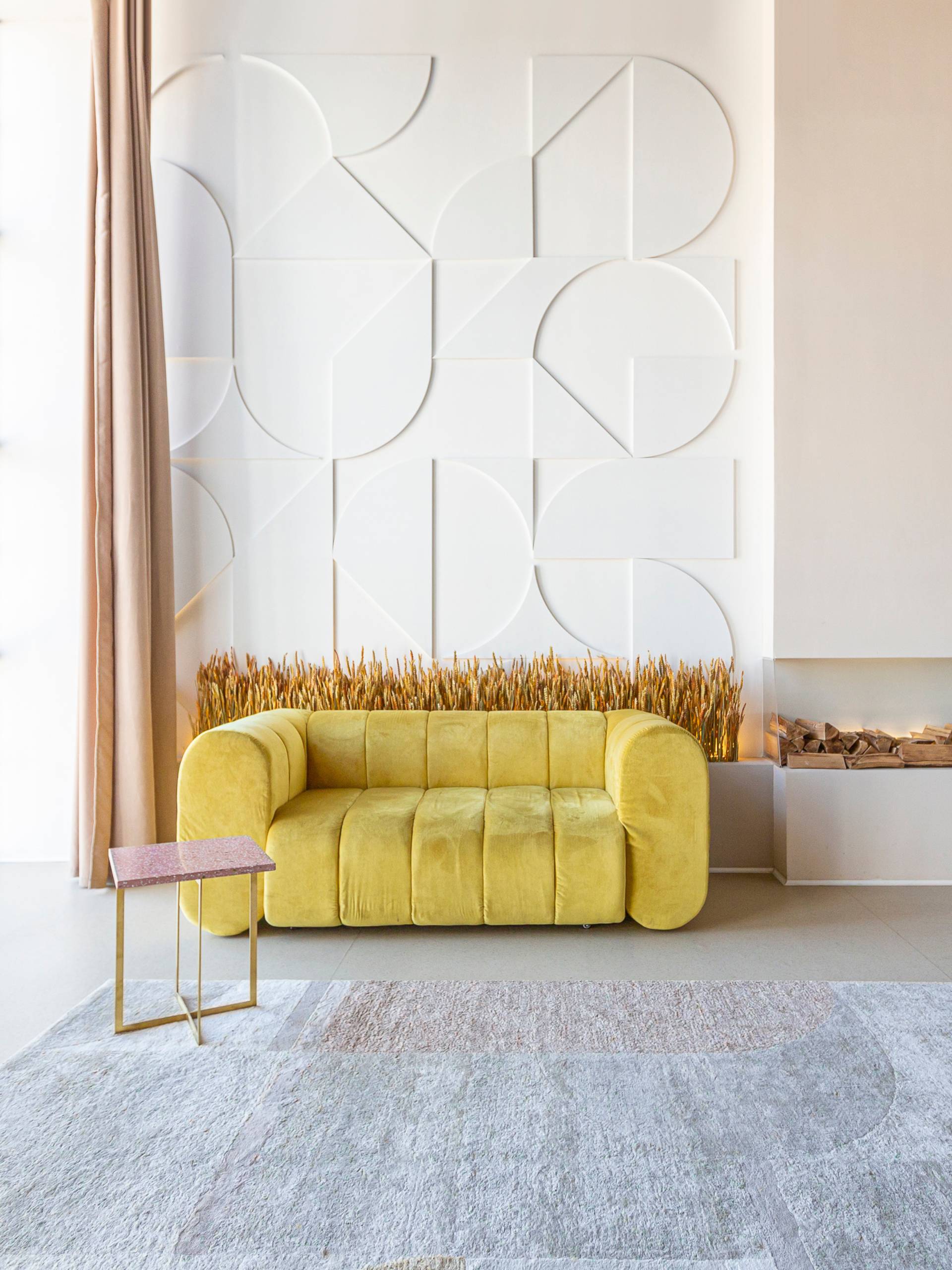 A modern loft apartment with large floor-to-ceiling windows, a yellow couch, and eccentric wall decor to the right.