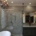 An updated bathroom with a chandelier hanging over the jacuzzi tub and warm pendant lights over the vanity.