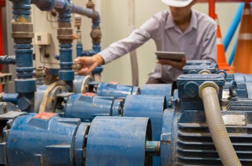 An operational technician working behind the scenes in a warehouse, servicing the industrial electric motors.