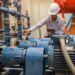 An operational technician working behind the scenes in a warehouse, servicing the industrial electric motors.