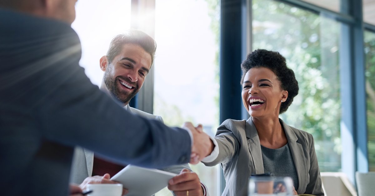 A business meeting with small business owners collaborating and shaking each others' hands. They're smiling and happy.