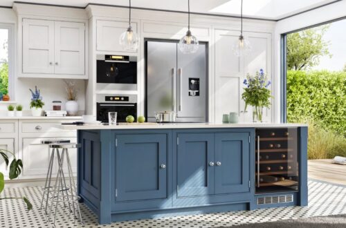 A modern kitchen with white cabinets, a blue center island, and stainless steel appliances on a sunny day.