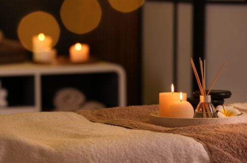 A spa table with candles and aromatic reed fresheners sitting on a tray. The table is covered by two plush towels.