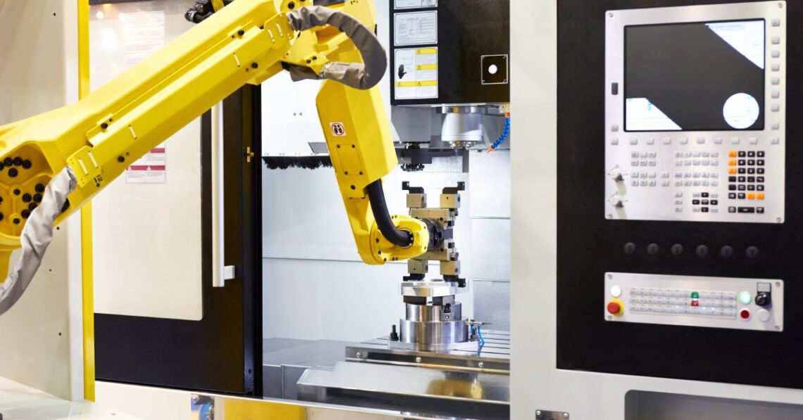 A yellow robotic arm placing an object onto a raised circular platform inside a conveyor belt behind an open door.