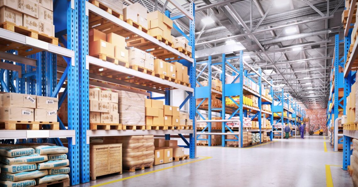 A large business warehouse with a bright blue racking system. Each rack is full of wrapped boxes and pallets.