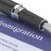 A black fountain pen sits on top of a document that says "Immigration" with the US Department of Homeland Security logo.
