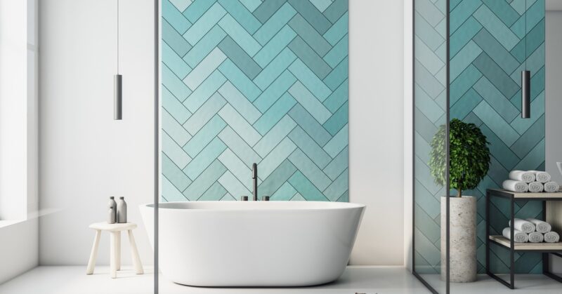 A modern bathroom with a white standalone tub, turquoise tiles, and a white bench. On the bench are bottles and a plant.