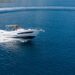 An aerial view of a luxury speed boat on the ocean making a sharp turn in the water. The boat created a curved wake.