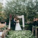 A beautiful fall wedding ceremony with chairs on the aisle, and a couple stands at the altar with flower petals in the aisle.