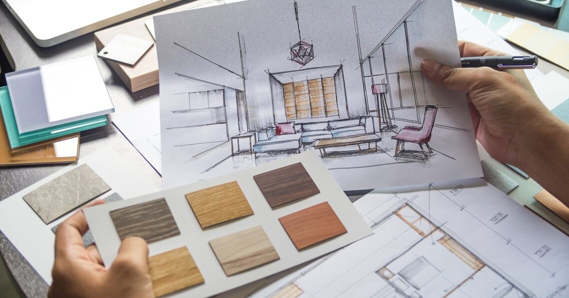 A person holds two papers. One is of a design sketch of a living room and the other has swatches of materials attached to it.