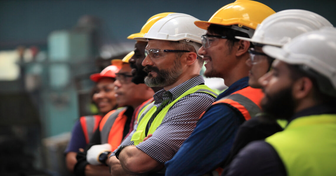 A line of engineers and maintenance team members staring forward and smiling. They are all wearing safety gear.