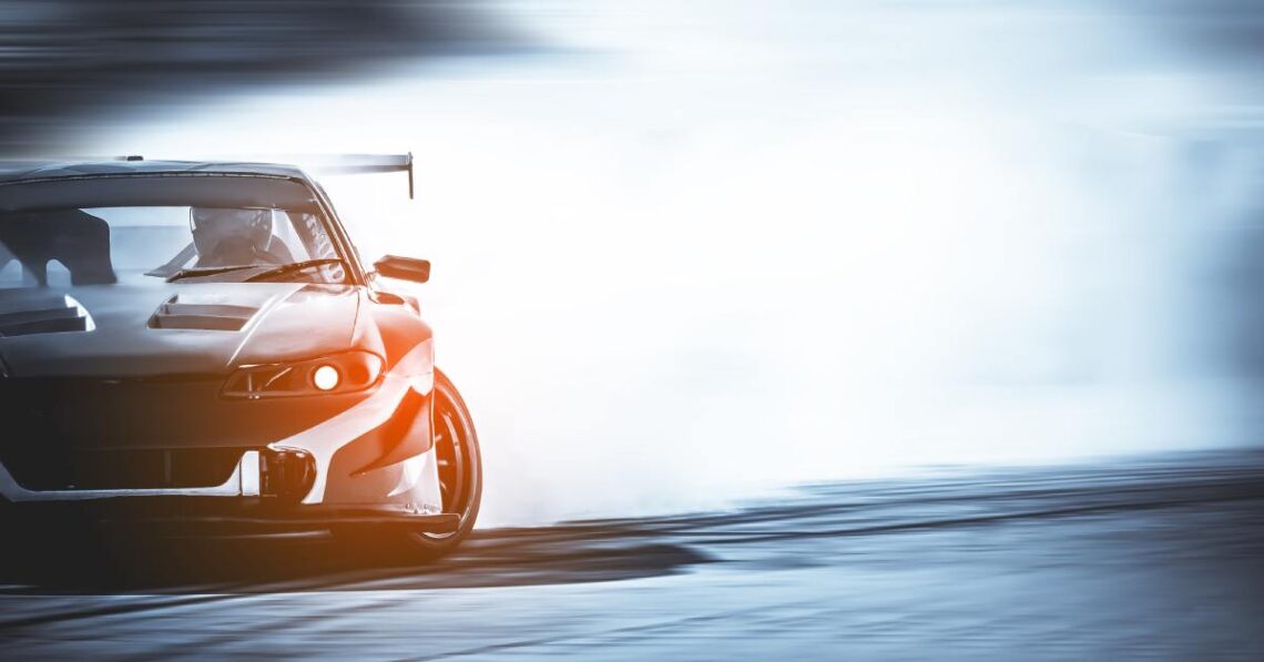 A high-performance sports car drifting on a track. The rear tires are smoking with the front wheels turned.
