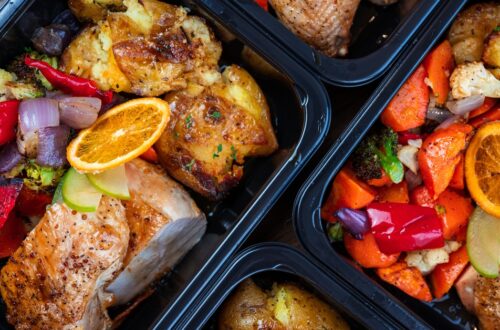Meal prep containers sit on the counter with lean chicken and vegetables fully cooked and seasoned.