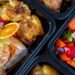 Meal prep containers sit on the counter with lean chicken and vegetables fully cooked and seasoned.
