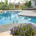 A luxury backyard pool with a rock feature and freshly groomed landscaping. The pool is curvy and bean-shaped.