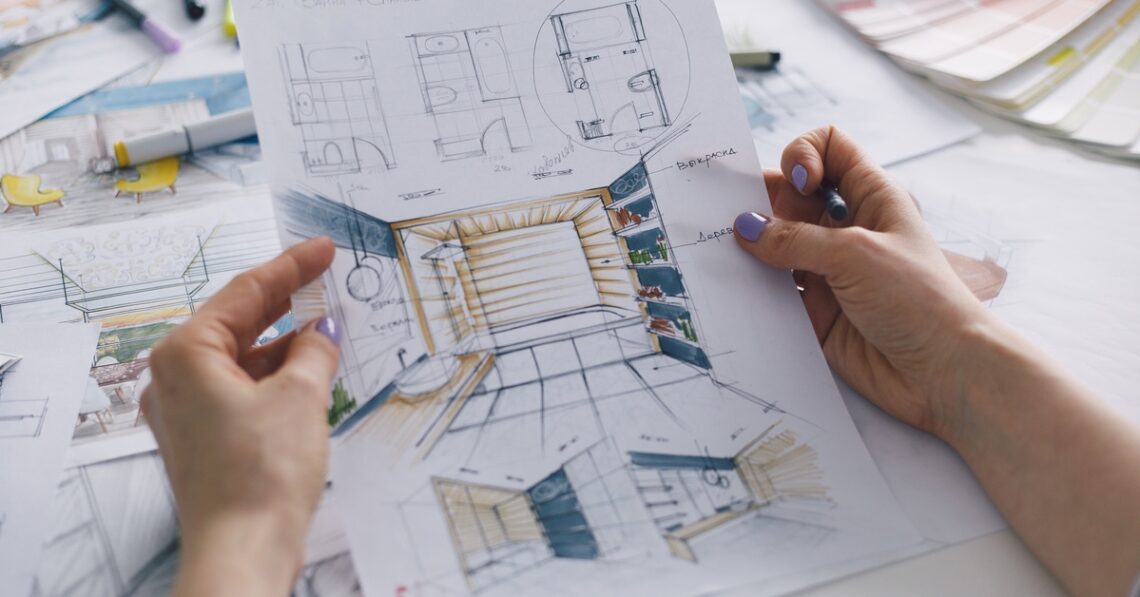 A person holding a blueprint for a residential bathroom remodel. The person’s nails are painted with purple nail polish.