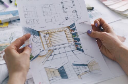 A person holding a blueprint for a residential bathroom remodel. The person’s nails are painted with purple nail polish.