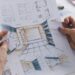A person holding a blueprint for a residential bathroom remodel. The person’s nails are painted with purple nail polish.