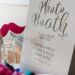 A photo booth setup with props beside a decorative sign reading “Photo Booth. Grab a prop, strike a pose, snap a pic”.
