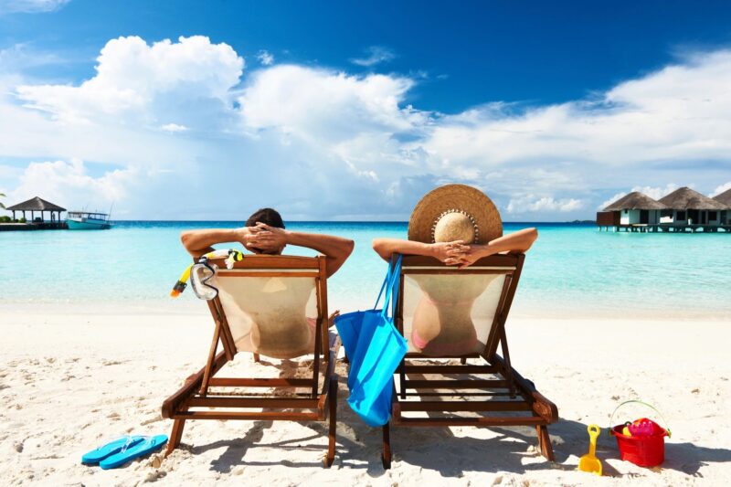 A couple at the beach in reclining chairs.