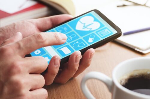 A pair of hands holding onto a smartphone with its screen on. The phone is next to a full cup of coffee.
