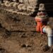 A dirt covered area with two pipe spickets coming out of the ground. The spickets have water shutoff valves.