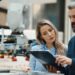 A businessman and engineer both looking at a clipboard the man is holding. There is a manufacturing robot behind them.