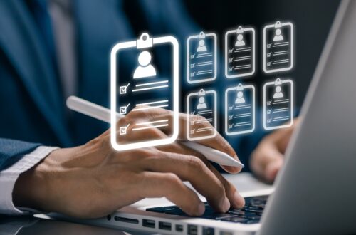 A recruiter working on a laptop. Small profile icons representing job candidates are displayed above the laptop.