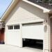 A sunny day in an alleyway with a two car garage. One garage door is shut and the other is half open.
