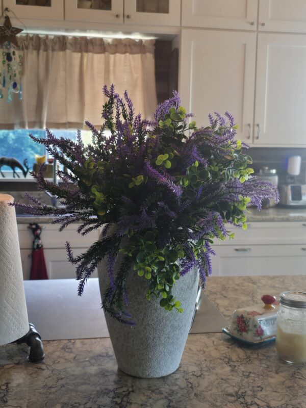 Purple flowering arrangement in a gray stone vase on a marble kitchen island, with green foliage. Vintage Ceramic Farmhouse Vase with Flowers. flower vase