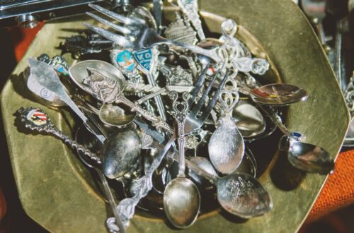 Metal bowl overflowing with assorted vintage silver spoons and forks.