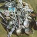 Metal bowl overflowing with assorted vintage silver spoons and forks.